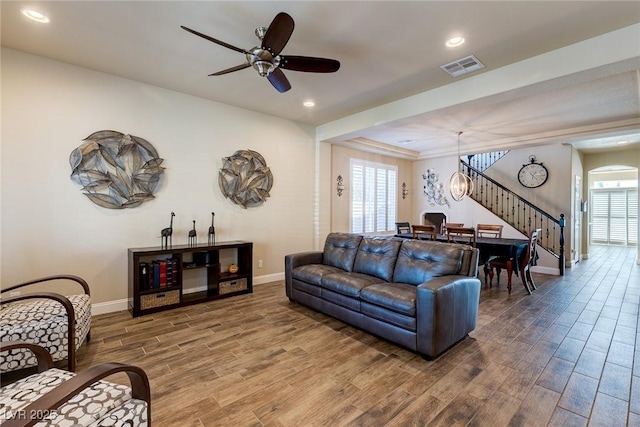 living area with visible vents, plenty of natural light, wood finished floors, and stairs