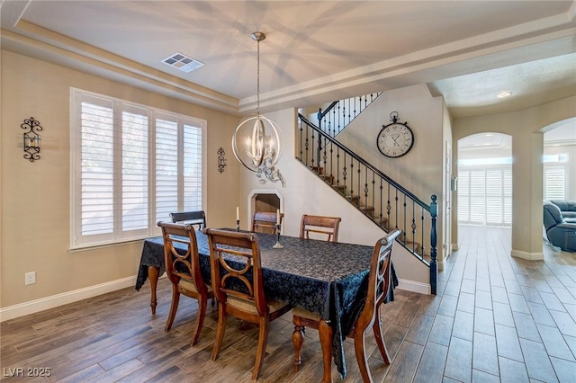 dining area featuring arched walkways, stairway, visible vents, and wood finished floors