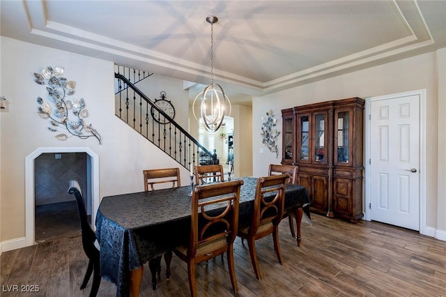 dining area featuring a tray ceiling, wood finished floors, and a chandelier