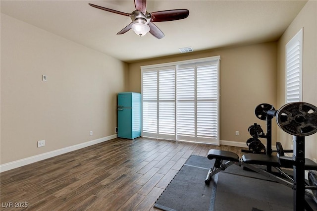 exercise room featuring visible vents, baseboards, wood finished floors, and a ceiling fan