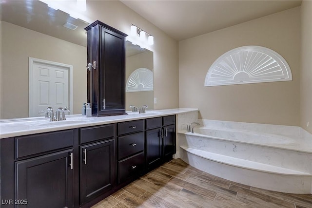 bathroom with a sink, double vanity, a garden tub, and wood tiled floor