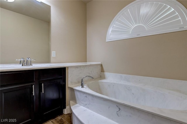 full bath with vanity, a garden tub, and wood finished floors