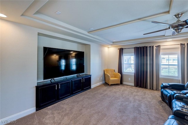 carpeted living room with a tray ceiling, baseboards, and ceiling fan