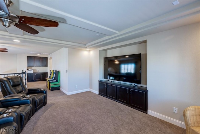 living room featuring baseboards, light carpet, a raised ceiling, and ceiling fan