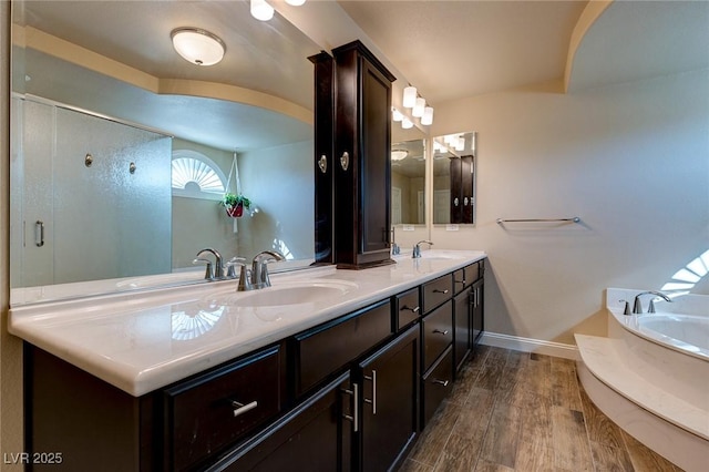 full bath featuring a garden tub, wood finished floors, double vanity, and a sink