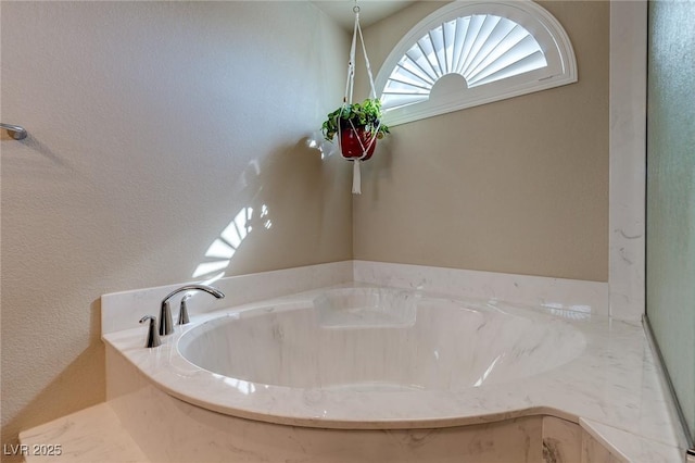 bathroom featuring a bath and a textured wall