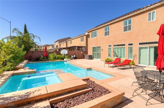 view of swimming pool featuring a patio, a fenced backyard, and a pool with connected hot tub