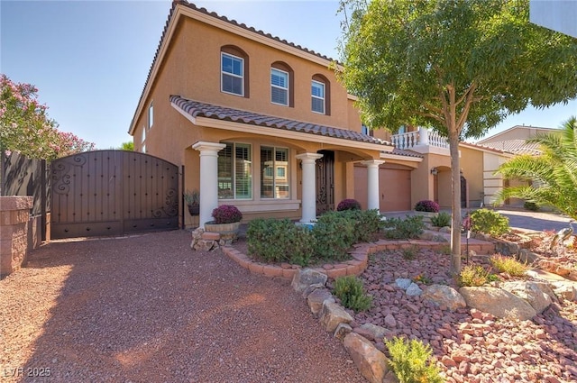 mediterranean / spanish house with stucco siding, a tile roof, and a gate