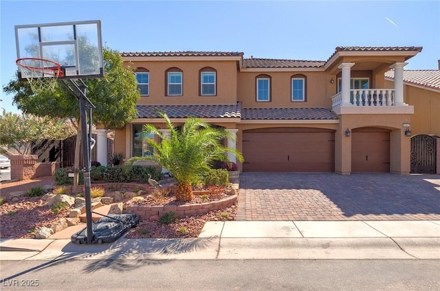 mediterranean / spanish house with a balcony, driveway, stucco siding, a garage, and a tiled roof