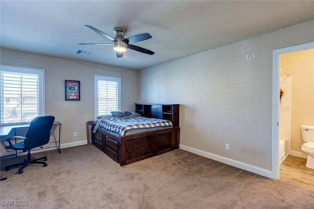 carpeted bedroom featuring visible vents, multiple windows, baseboards, and ensuite bath