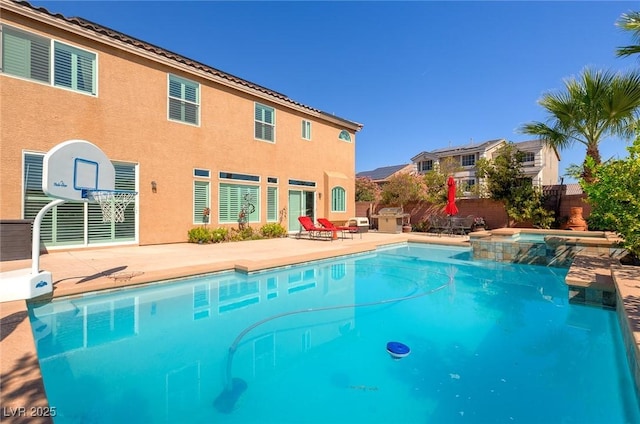 view of pool featuring a patio, fence, and a pool with connected hot tub