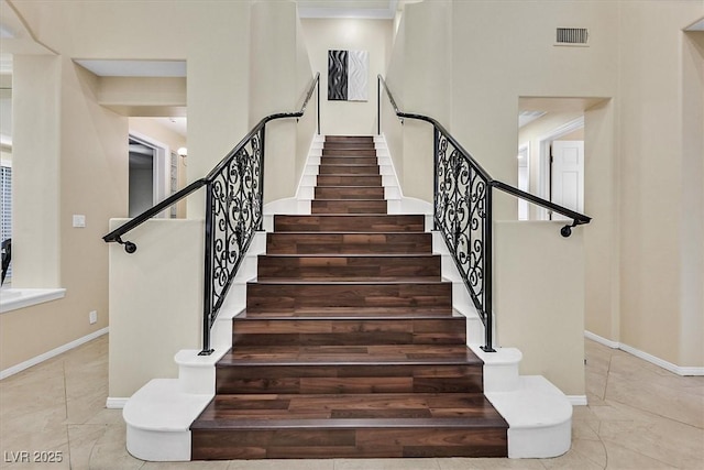 stairway with visible vents, baseboards, and tile patterned flooring