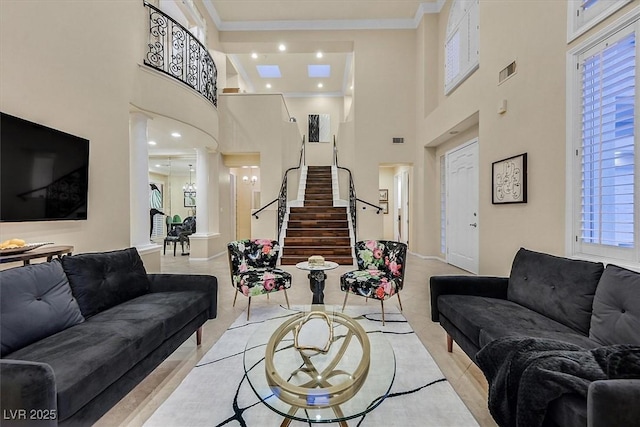 living room featuring stairway, visible vents, a towering ceiling, crown molding, and a wealth of natural light