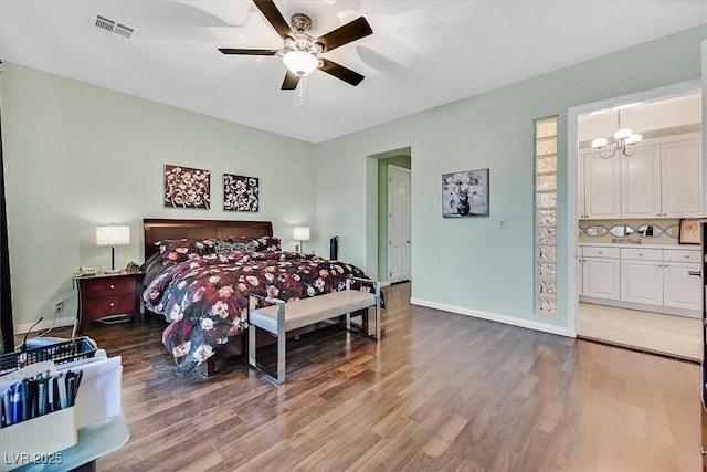 bedroom with visible vents, a ceiling fan, ensuite bath, wood finished floors, and baseboards