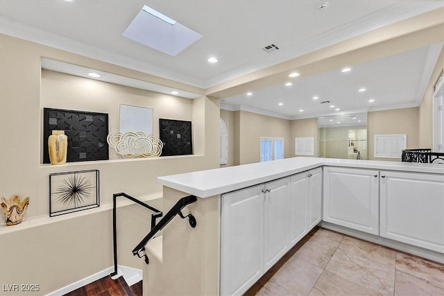 kitchen with visible vents, light countertops, ornamental molding, a skylight, and white cabinets