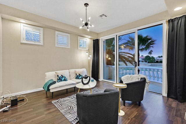 living room featuring a chandelier, baseboards, visible vents, and wood finished floors