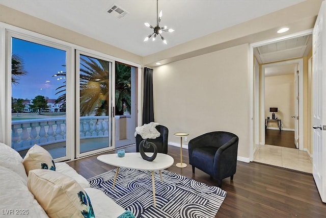 living area featuring visible vents, baseboards, a notable chandelier, and wood finished floors