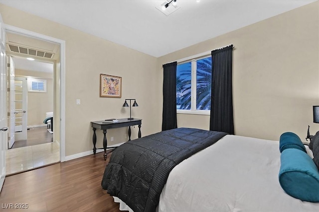 bedroom with wood finished floors, visible vents, and baseboards