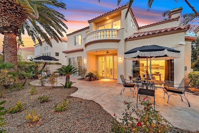 back of property featuring a patio, a balcony, french doors, and a tile roof