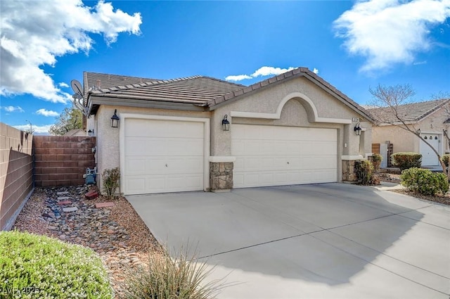 view of front of house featuring fence, a tile roof, concrete driveway, stucco siding, and a garage