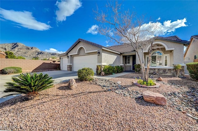 view of front of home featuring stucco siding, an attached garage, driveway, and fence