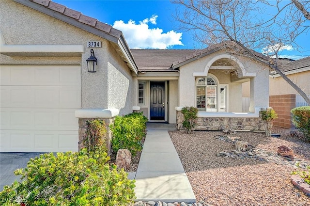 entrance to property featuring stucco siding, an attached garage, and a tile roof