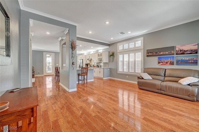 living room featuring crown molding, visible vents, light wood-type flooring, and baseboards