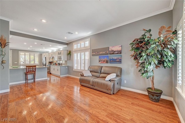 living area featuring light wood finished floors, visible vents, baseboards, ornamental molding, and recessed lighting