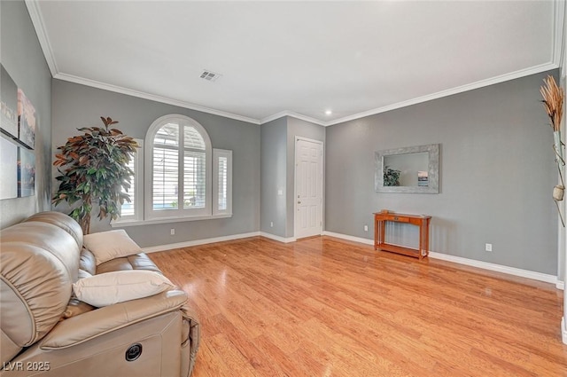 living room with crown molding, wood finished floors, baseboards, and visible vents