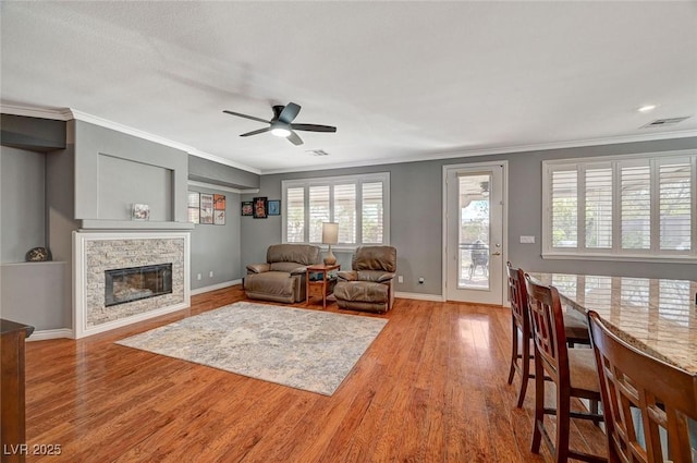 living room featuring visible vents, a ceiling fan, wood finished floors, and crown molding