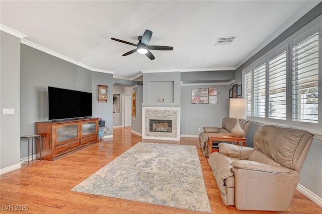 living area with light wood-type flooring, visible vents, a fireplace, baseboards, and ceiling fan