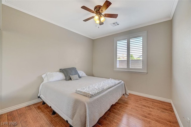 bedroom featuring visible vents, crown molding, baseboards, and wood finished floors