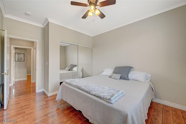 bedroom with crown molding, baseboards, light wood-type flooring, and a closet