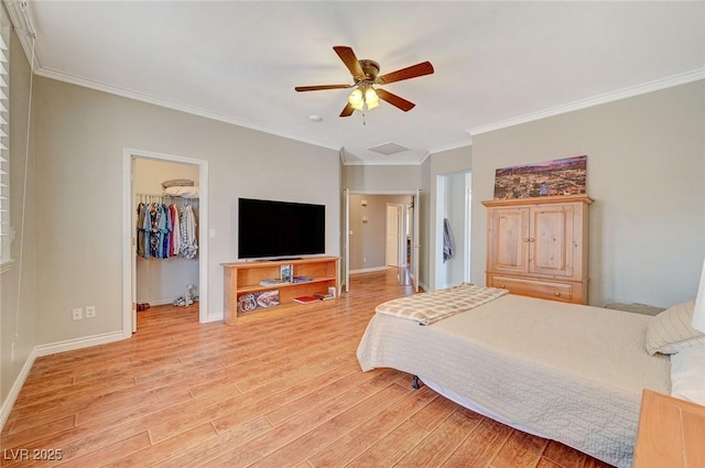 bedroom with baseboards, ornamental molding, a spacious closet, and light wood finished floors