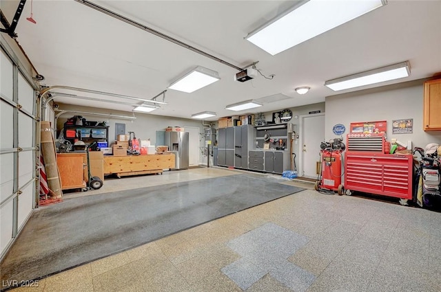 garage featuring a garage door opener and stainless steel refrigerator with ice dispenser