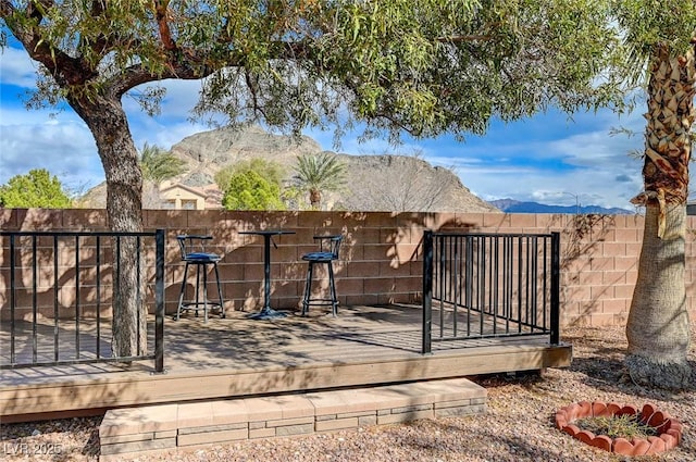 view of gate featuring a deck with mountain view and a fenced backyard