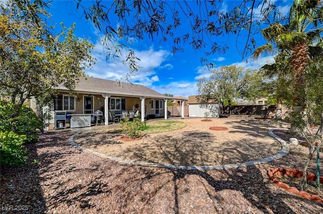 rear view of property with a patio area, fence, an outdoor structure, and stucco siding