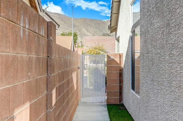 exterior space with a mountain view, fence, stucco siding, and a gate