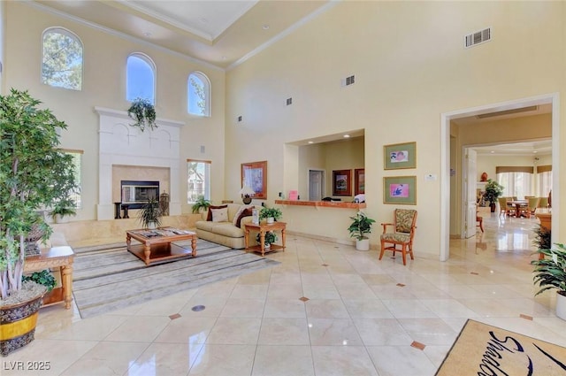 tiled living area featuring visible vents, baseboards, ornamental molding, and a high end fireplace