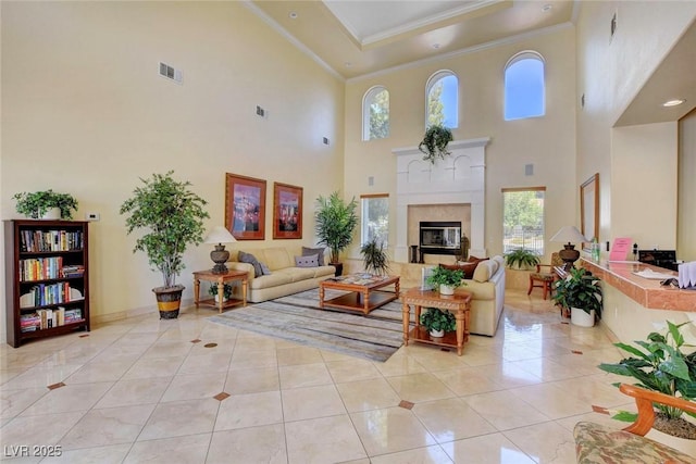 living area with light tile patterned flooring, a tile fireplace, visible vents, and ornamental molding