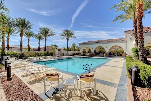 pool with a patio area and fence