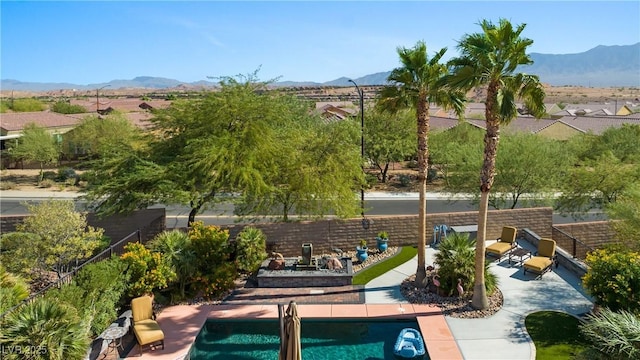 outdoor pool featuring a mountain view, a patio, and fence