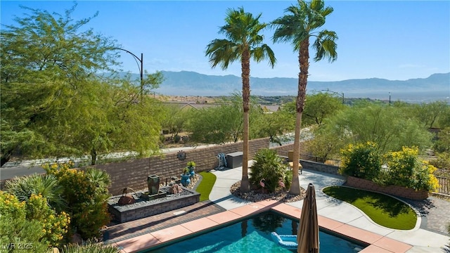 view of swimming pool with a patio, a fenced in pool, a fenced backyard, and a mountain view