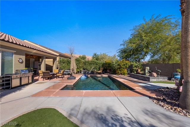 view of swimming pool with a fenced in pool, fence, a patio area, area for grilling, and an outdoor kitchen