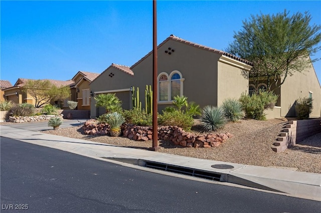 mediterranean / spanish-style house with stucco siding, a garage, and a tile roof