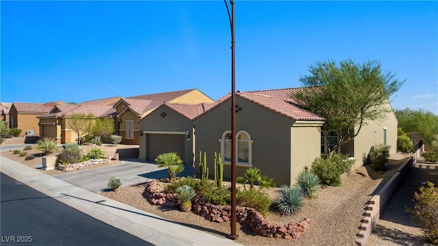 mediterranean / spanish house featuring stucco siding, a residential view, concrete driveway, an attached garage, and a tiled roof