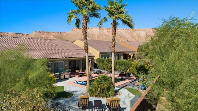 rear view of property featuring an outdoor pool, stucco siding, a patio, and a tile roof