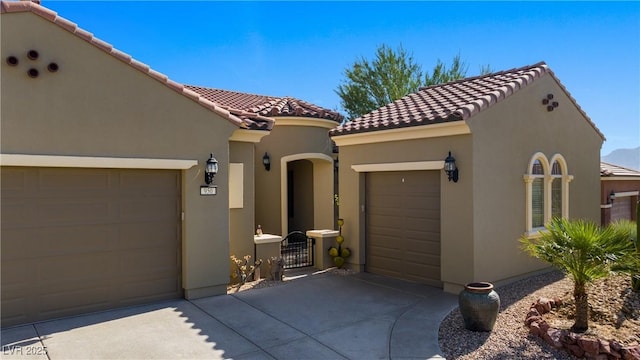 view of front of home with stucco siding, concrete driveway, an attached garage, and a tile roof