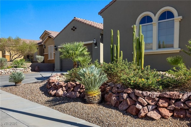 view of home's exterior with a tiled roof, stucco siding, and an attached garage