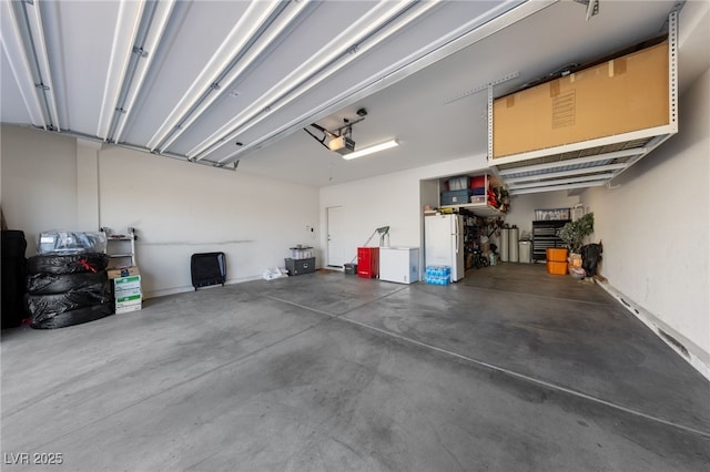 garage with a garage door opener and freestanding refrigerator